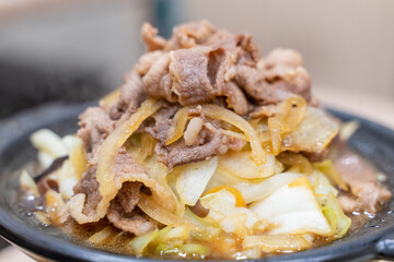 A traditional Asian clay pot rice dish is served piping hot, nestled in a rustic earthenware pot. Steam rises from the sizzling surface, revealing layers of tender sliced meat, crisp bean sprouts