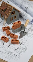 House Construction Blueprint with Miniature House Model and Bricks
