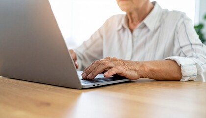 An elderly person working on a laptop, showcasing the use of technology across generations. The hands are positioned on the keyboard