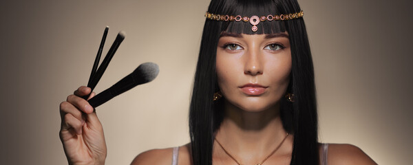 Regal Cleopatra-Inspired Woman Holding Makeup Brushes - Banner