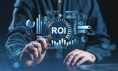 Businessman analyzing ROI with virtual data graphics in futuristic interface concept on dark...