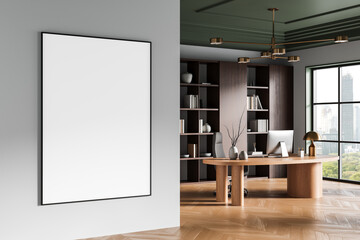 Blank framed poster mockup on clean wall in stylish modern office interior with wooden desk, bookshelves, and city view through large window. 3D Rendering
