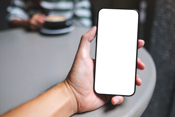 Mockup image of a man holding mobile phone with blank white screen in cafe
