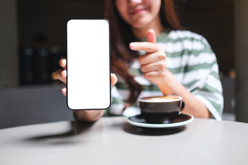 Mockup image of a beautiful woman pointing finger at a mobile phone with blank white screen