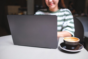 Closeup image of a woman working and typing on laptop computer in cafe