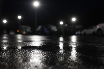 A blurry image of a parking lot at night with cars and a street light