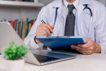 doctor reviewing patient documents with a pen in hand, showcasing the balance between traditional paperwork and modern healthcare technology in a medical office.