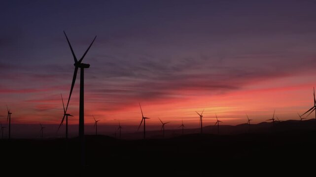 Wind turbines on rolling hills at dusk in Altamont Pass, Livermore, California, USA. The turbines are generating clean, renewable energy for the power grid.