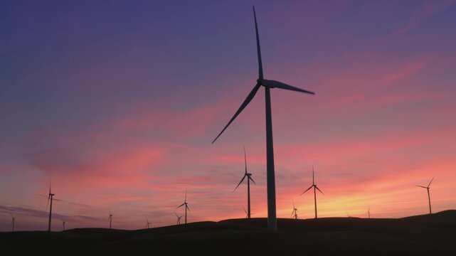 Wind turbines stand silhouetted against a vibrant sunset sky in Altamont Pass, Livermore, California, USA. These turbines convert wind energy into electricity, promoting renewable energy.