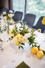 Festive table decor in yellow and white tones with flowers and lemons.