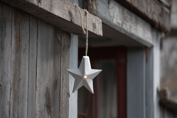 delicate star suspended from soft rope against backdrop of wooden wall in pastel tones
