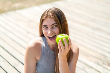 Young pretty caucasian woman holding an apple with happy expression