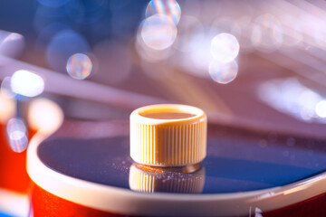 Knob on a vibrant electric guitar, with a glossy finish reflecting its surroundings. Background...