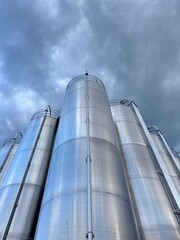 Large stack of silver tanks with a cloudy sky in the background