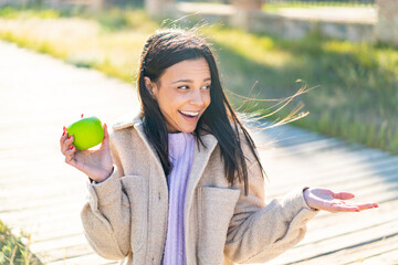 Young woman with an apple at outdoors with surprise facial expression