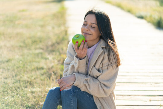 Young woman at outdoors holding an apple