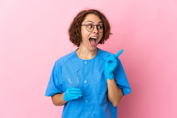 Woman English dentist holding tools over isolated on pink background intending to realizes the...