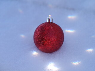Red ornament is sitting on top of a snowy surface