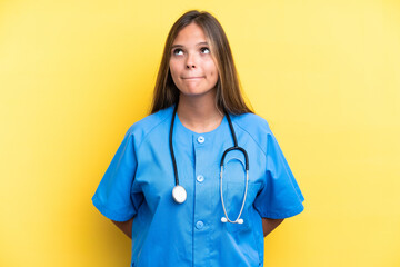 Young nurse caucasian woman isolated on yellow background and looking up