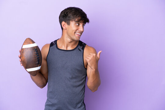 Young man playing rugby isolated on purple background pointing to the side to present a product - Powered by Adobe