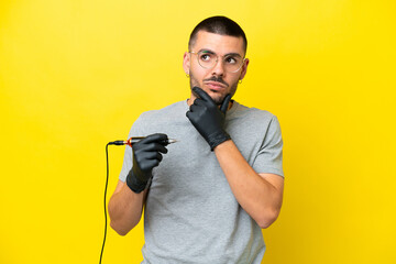Tattoo artist caucasian man isolated on yellow background having doubts