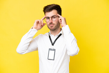 Young caucasian with ID card isolated on yellow background having doubts and thinking