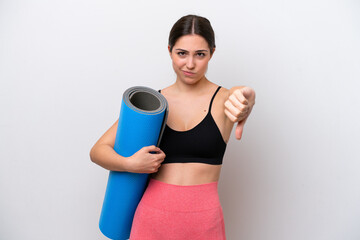 Young sport girl going to yoga classes while holding a mat isolated on white background showing...