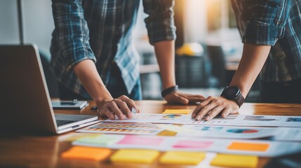 Obraz premium Team analyzes data on table. Business partners collaborate, plan strategy. Workplace. Marketing, web, design, editorial use.