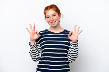 Young reddish woman isolated on white background showing ok sign with two hands