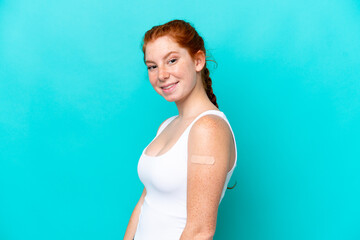 Young reddish woman wearing a band aids on blue background smiling a lot