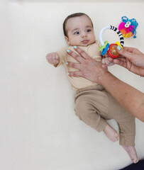 Early rehabilitation for baby with therapist guiding attention and movement using a bright rattle...
