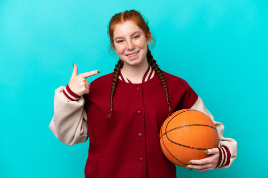 Young reddish woman playing basketball isolated on blue background giving a thumbs up gesture