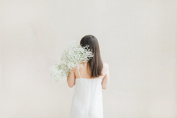 Woman Holding White Flowers Against Neutral Background