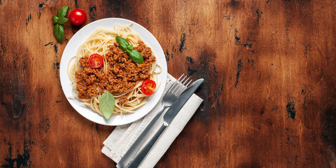 Pasta Spaghetti Bolognese in white plate on wooden background. Bolognese sauce is classic italian cuisine dish. Popular italian food. Top view
