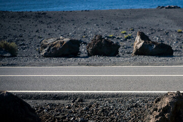 A beautiful asphalt road among black volcanic landscapes with lava formations.