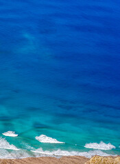 Obraz premium Blue ocean with waves and a sandy beach, top view.