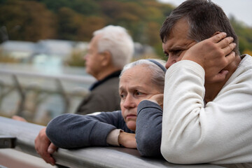 An elderly man and a woman with sad faces outdoor.