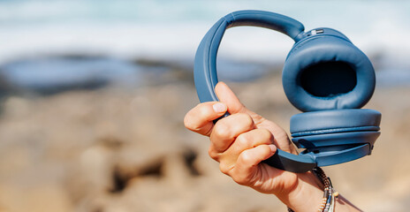 A girl holds a wireless headphones in hands, closeup view.
