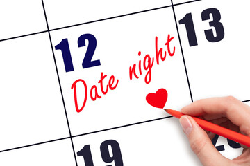 12th day of the month.  Hand writing Date night reminder and drawing a red heart on calendar with...
