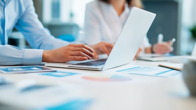 Business professionals analyze data using laptop in bright office. Modern, teamwork, workspace. For web use, marketing, design.