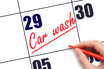 29th day of the month.  Hand writing Car wash reminder and drawing a line on calendar with red pen...