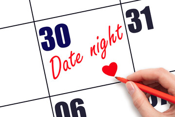 30th day of the month.  Hand writing Date night reminder and drawing a red heart on calendar with...