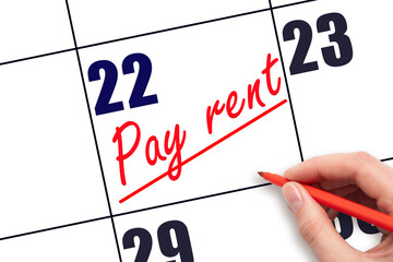22nd day of the month.  Hand writing Pay rent reminder and drawing a line on calendar with red pen...