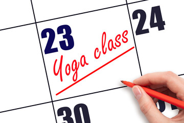 23rd day of the month.  Hand writing Yoga class reminder and drawing a line on calendar with red...