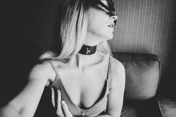 Sexy nude young woman with black mask posing on the sofa