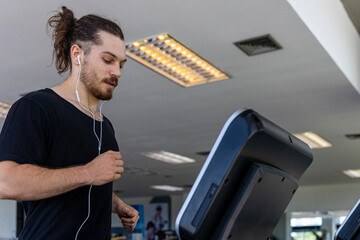 Smart fitness trainer shows how to use treadmill to improve leg strength and building muscles in a gym. A sport man is running on a treadmill to start his workout program.