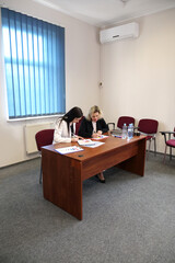 Two business women work in the office to solve problems and sign agreements.