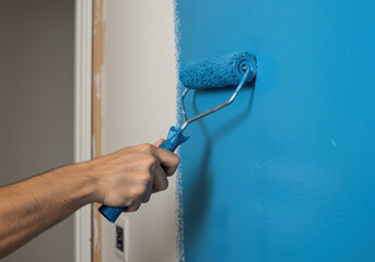 Male hand painting wall with blue paint roller. Painting apartment, renovating concept