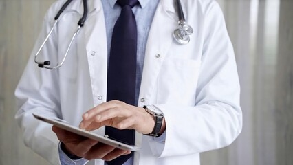 Doctor man wearing lab coat and stethoscope using tablet computer in hospital. Medicine and science