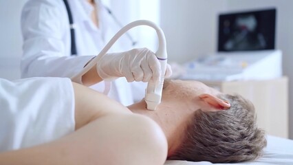 Doctor woman wearing white medical coat performing neck ultrasound exam on male patient. Medicine...